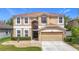 Charming two-story tan home with a well-manicured lawn and a two-car garage at 18441 New London Ave, Land O Lakes, FL 34638