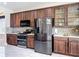 Spacious kitchen featuring stainless steel appliances, wood cabinetry, and a view into a dining area at 18441 New London Ave, Land O Lakes, FL 34638
