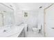 Well-lit bathroom featuring a toilet, washer/dryer, vanity, and a decorative mirror at 13116 Boca Ciega Ave, Madeira Beach, FL 33708