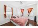 Cozy bedroom with three windows, wood floors, ceiling fan and light pink bed spread at 13116 Boca Ciega Ave, Madeira Beach, FL 33708