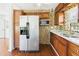Spacious kitchen featuring stainless refrigerator, granite countertops, wood cabinets and mosaic tile backsplash at 13116 Boca Ciega Ave, Madeira Beach, FL 33708