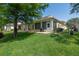Backyard with a well-manicured lawn and light yellow house with screened-in back porch at 1188 Royal Blvd, Palm Harbor, FL 34684