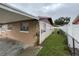 Side view of home featuring tan and white paint, white trim, and a stone accent pillar, along with a grassy yard at 6019 W Fern St, Tampa, FL 33634