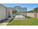 A view of the screened-in pool and patio from the grassy backyard with brick wall at 6335 Cardinal Crest Dr, New Port Richey, FL 34655