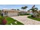 Welcoming home with a two-car garage, brick driveway, lush lawn, and trimmed landscaping at 1120 81St S St, St Petersburg, FL 33707