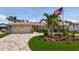 Charming home featuring a circular brick driveway, lush lawn, mature palms, and decorative landscaping at 1120 81St S St, St Petersburg, FL 33707