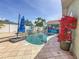 Backyard pool area featuring a spa, blue umbrellas, and colorful potted flowers on the patio at 1120 81St S St, St Petersburg, FL 33707