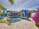 Backyard pool with a jacuzzi, tropical plants, and screened-in lanai for seamless indoor/outdoor living at 1120 81St S St, St Petersburg, FL 33707