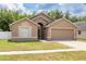 Exterior shot of a tan single-story home with a two-car garage and well-manicured front lawn at 18941 Twinberry Dr, Tampa, FL 33647