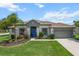 Charming single-story home with a manicured lawn, lush landscaping, and a vibrant blue front door at 13365 Chesapeake Pl, Spring Hill, FL 34609