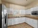 Community center kitchen featuring white cabinets, stainless steel appliances, tan countertops, and tile floor at 13365 Chesapeake Pl, Spring Hill, FL 34609