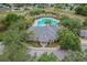 Aerial view of a clubhouse and community pool, surrounded by lush landscaping and trees in a neighborhood at 13365 Chesapeake Pl, Spring Hill, FL 34609