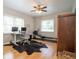 Bedroom with hardwood flooring, ceiling fan, dual monitor desk, and workout equipment by the window at 18101 Boy Scout Rd, Odessa, FL 33556