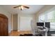 Bedroom featuring hardwood floors, ceiling fan, and dual monitor desk, with views of the backyard through the windows at 18101 Boy Scout Rd, Odessa, FL 33556