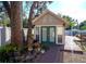 An exterior view shows a charming outbuilding, enhanced by greenery, a walkway, and a striking front door at 18101 Boy Scout Rd, Odessa, FL 33556