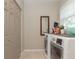 Functional laundry room with a modern washer and dryer, storage closet, and a bright window at 18101 Boy Scout Rd, Odessa, FL 33556