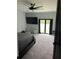 Cozy bedroom featuring plush carpeting, a ceiling fan, flatscreen TV, and a glass patio door with backyard view at 2518 Sunset Ln, Lutz, FL 33559