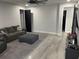 An open-concept living room featuring a gray sofa and ottoman, with doorways leading to other areas of the home at 2518 Sunset Ln, Lutz, FL 33559