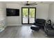 Contemporary living room featuring gray wood-look tile flooring, a ceiling fan, and modern black-framed windows at 2518 Sunset Ln, Lutz, FL 33559