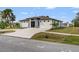 An eye-level view of a modern home with a circular driveway, palm trees, and desert landscaping at 5479 S Biscayne Dr, North Port, FL 34287