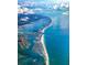 Stunning aerial view of the coastline featuring bright ocean waters and gorgeous beach homes under a cloudy sky at 891 Island Way, Clearwater Beach, FL 33767