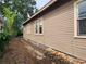 Side exterior view of a home featuring wood siding, brick accents and mature trees at 917 E 15Th Ave, Tampa, FL 33605
