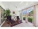 Bright sunroom featuring two armchairs, sliding glass doors, and views of the landscaped backyard at 6948 W Country Club N Dr, Sarasota, FL 34243