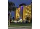 Well-lit, multi-story building featuring balconies, palm trees and a grassy area at night at 4750 Cove Cir # 502, St Petersburg, FL 33708