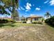Expansive backyard featuring a screened-in lanai, lush green grass, and mature trees at 1052 Archway Dr, Spring Hill, FL 34608