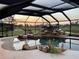 Tranquil pool with rock features under a screened enclosure offering relaxing views of the water and landscape beyond at 536 Boundary Blvd, Rotonda West, FL 33947