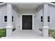 Close up of front of home with gray exterior, black double doors, covered porch area, and lush green grass at 14 S Forest St, Plant City, FL 33563