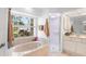 Bright bathroom features a tub under a window and a separate glass-enclosed shower at 23338 Duchess Ave, Port Charlotte, FL 33954