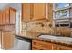 Kitchen featuring wood cabinets, granite countertops, a stainless steel dishwasher, and a sink at 4317 S Trask St, Tampa, FL 33611