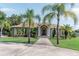Charming home featuring a lush, green lawn, palm trees, and an inviting walkway to the beautiful double-door entrance at 2638 E Knights Griffin Rd Rd, Plant City, FL 33565