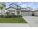 Two-story home with gray siding, three-car garage, and landscaped lawn at 11449 Owasee Trails Pl, Riverview, FL 33569