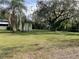 Spacious backyard with shade trees, grassy area, and home exterior at 750 Charlie Taylor Rd, Plant City, FL 33566