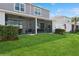 Backyard view of screened patios on townhomes overlooking a lush green lawn and palm trees at 11658 Bluestone Ct, Parrish, FL 34219