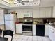 Bright kitchen features white cabinets, stainless steel appliances, and tile flooring at 11231 Dollar Lake Dr # 1, Port Richey, FL 34668