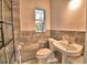 Bathroom with a pedestal sink, toilet, and shower with glass door and marbled walls at 1413 May St, Lutz, FL 33548
