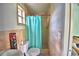 Bathroom features a toilet and shower with teal curtain, and tiled walls at 1413 May St, Lutz, FL 33548