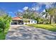 Charming single-story home with covered parking and a spacious driveway, set against a backdrop of mature trees and blue skies at 1413 May St, Lutz, FL 33548