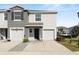 Contemporary townhome featuring a two-car garage, neutral stucco exterior, and well-maintained landscaping at 8680 Falling Blue Pl, Riverview, FL 33578
