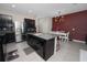 Kitchen features a granite island, stainless steel appliances, and dark cabinetry, blending style with functionality at 8680 Falling Blue Pl, Riverview, FL 33578