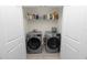 Laundry closet with two modern washer and dryers and storage shelf at 8680 Falling Blue Pl, Riverview, FL 33578