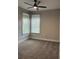 Cozy bedroom with neutral carpeting, two large windows, and a ceiling fan at 8623 Snowy Owl Way, Tampa, FL 33647