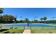 A pristine blue and green tennis court under a bright blue sky with lush landscaping at 8623 Snowy Owl Way, Tampa, FL 33647