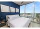 Bedroom with bright blue accent wall, white bedding and floor to ceiling window with city view at 777 N Ashley Dr # 2313, Tampa, FL 33602