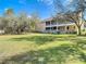 Beautiful backyard shows a home with a screened porch, surrounded by large trees and lush greenery at 11175 Hyde St, Weeki Wachee, FL 34614