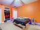 Bedroom with vivid orange walls, lit closet, and ceiling fan showcasing room's potential at 11175 Hyde St, Weeki Wachee, FL 34614