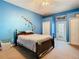 Bedroom featuring bright blue walls, ceiling fan, walk-in closet, and sliding glass door access to the patio at 11175 Hyde St, Weeki Wachee, FL 34614